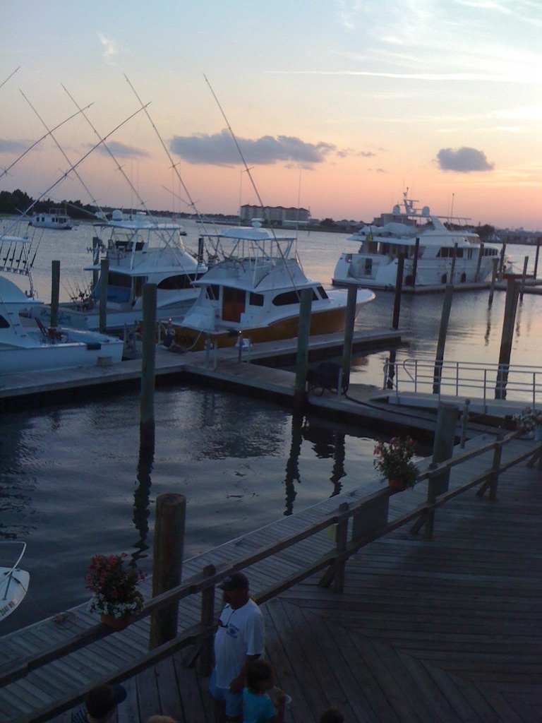 Sportfishing boats with tall outriggers docked at the Beaufort, North Carolina waterfront at sunset.