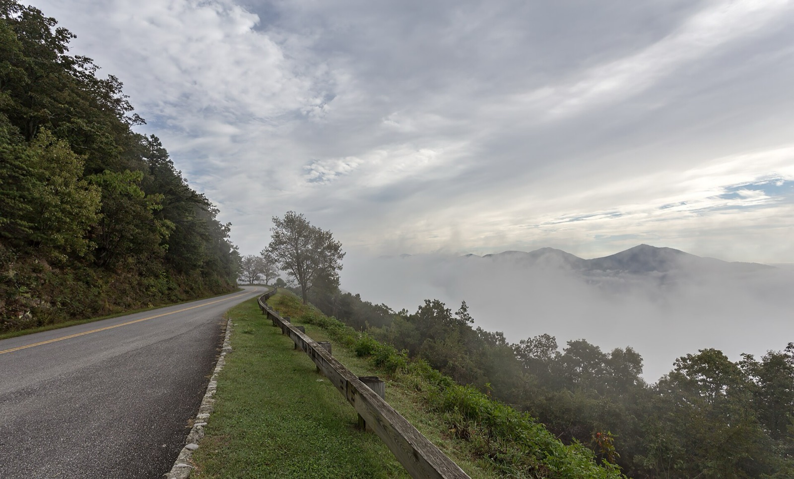 The Blue Ridge Parkway winding through mountains ablaze with October color, ridgelines fading into blue distance.