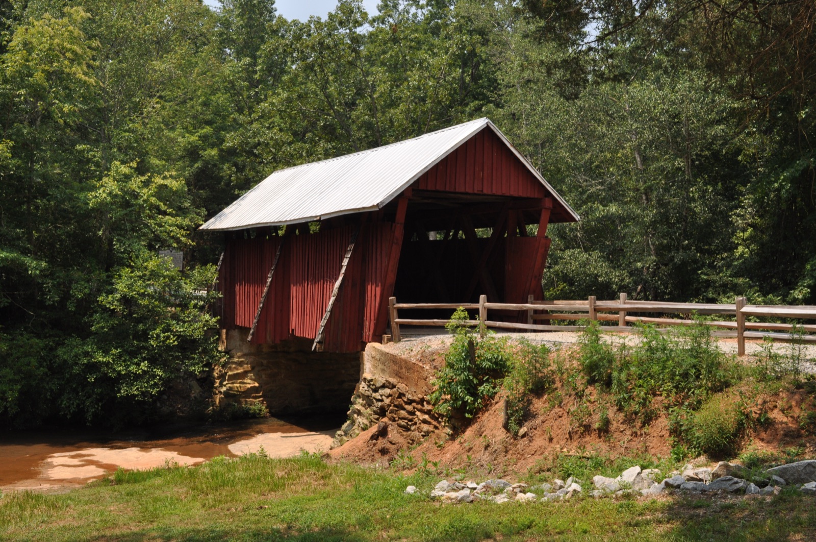 Campbell's Covered Bridge, a red wooden covered bridge in the South Carolina foothills, in summer.