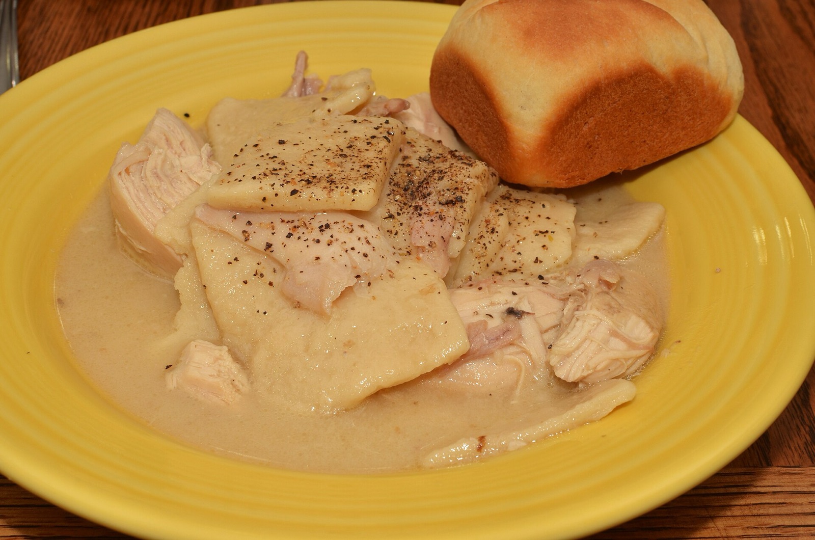 A bowl of chicken and dumplings, thick and steaming, pulled from a well-worn pot on the stove.