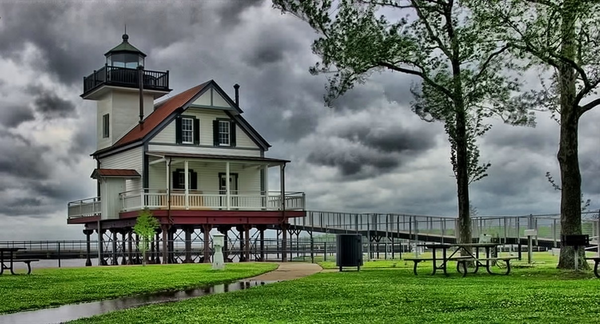 The historic white Roanoke River Lighthouse on the waterfront at Edenton, North Carolina, under a dramatic sky.