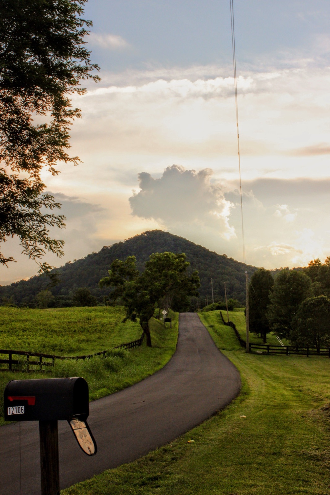 A scenic rural road leading toward distant green hills.