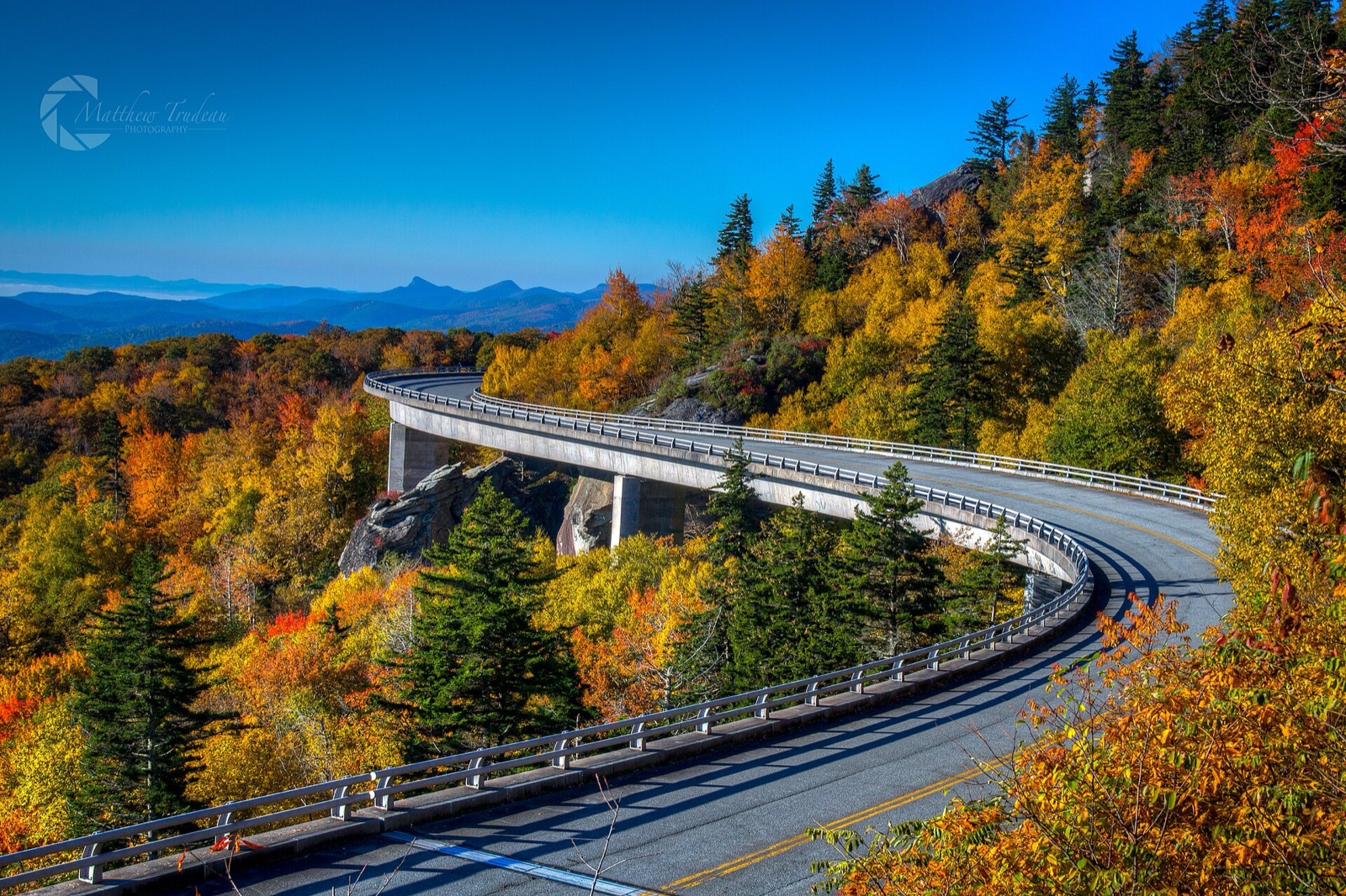 The curving Linn Cove Viaduct sweeping around the flank of Grandfather Mountain above forest.