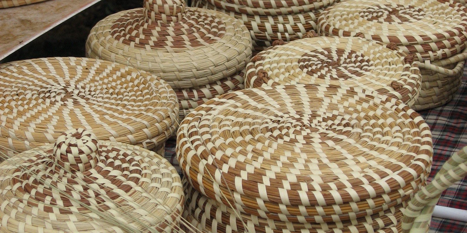 Coiled sweetgrass baskets with lids displayed on a table in the South Carolina Lowcountry.