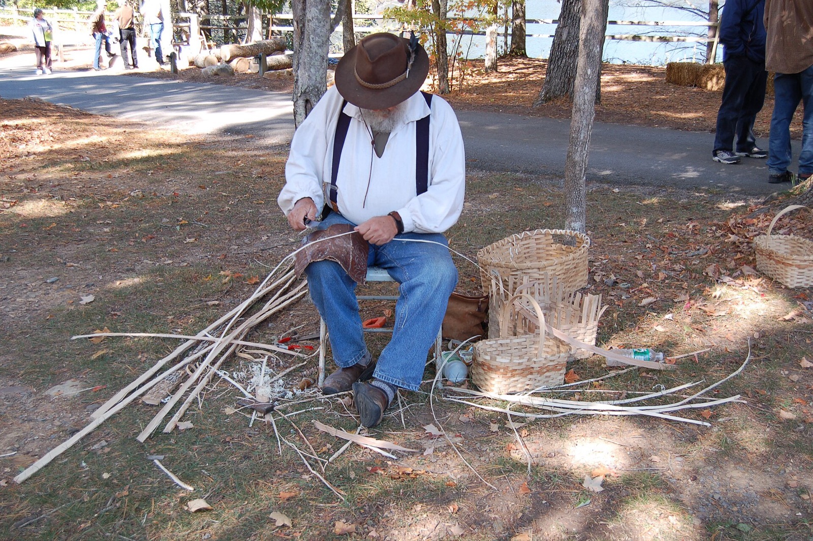 A mountain craftsman's hands weaving a white oak basket from pale split splints, shavings on the bench.